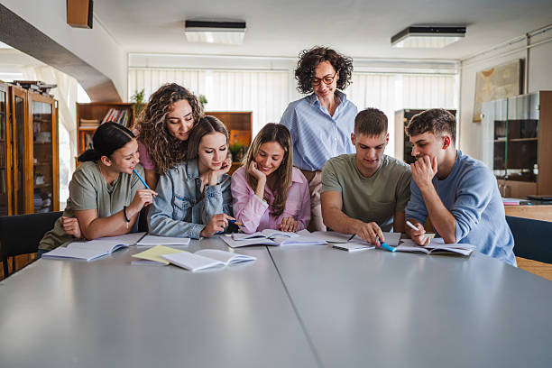 istock Group of high school students work on project with teacher in library 2217009562