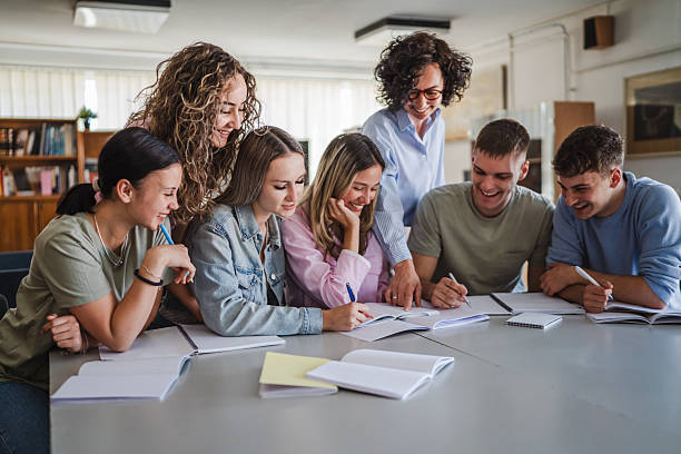 istock Group of high school students work on project with teacher in library 2217009595