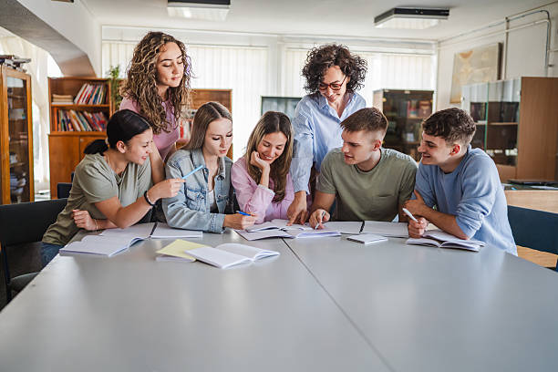 istock Group of high school students work on project with teacher in library 2217009616