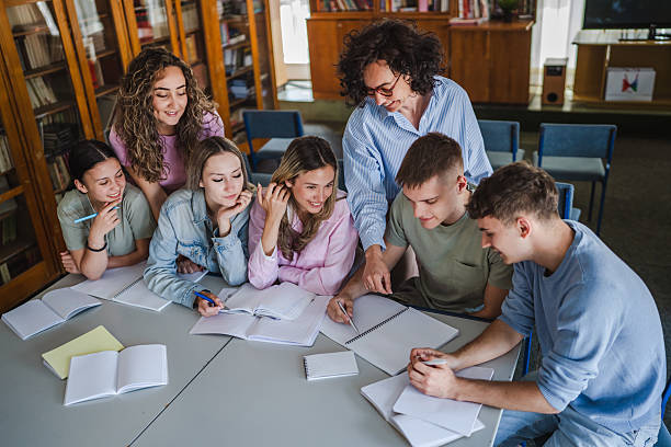 istock Group of high school students work on project with teacher in library 2217009651
