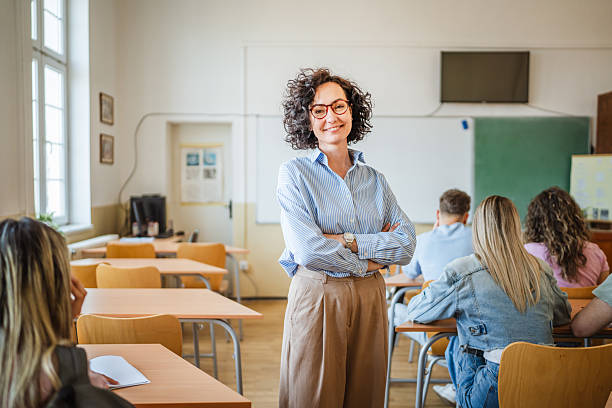 istock A mature female teacher stand confidently in her elementary classroom 2217010753