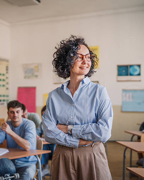 istock A mature female teacher stand confidently in her elementary classroom 2217011216