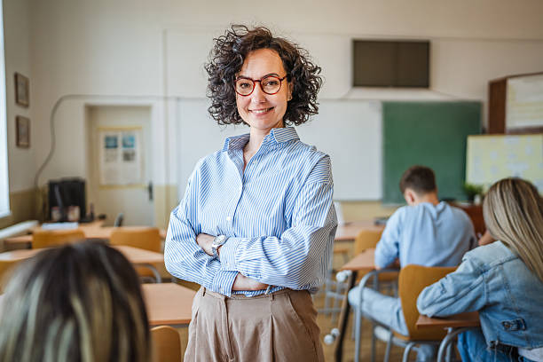istock A mature female teacher stand confidently in her elementary classroom 2217011679