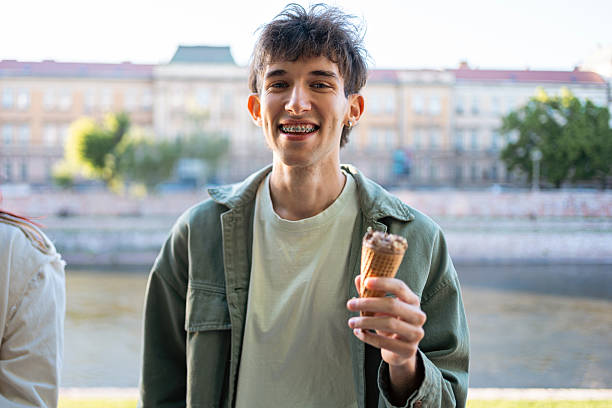 istock Young man smiling while enjoying an ice cream cone outdoors by a river 2217011773