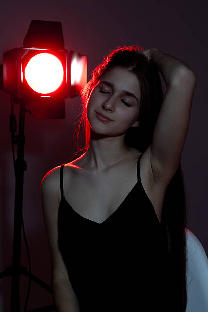 istock Young woman in black outfit posing under red spotlight in a minimalistic setting during a portrait session 2217013199