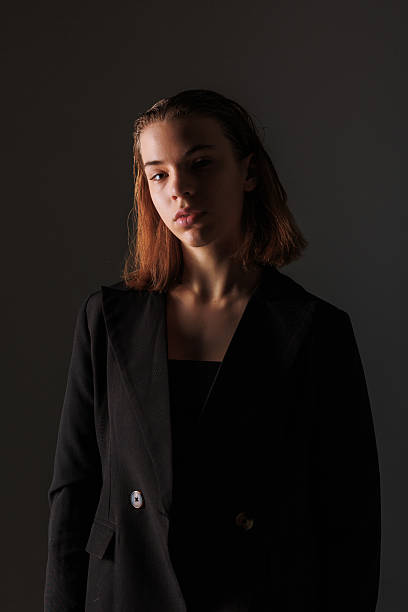 istock Model poses in stylish outfit against dark backdrop with soft lighting during indoor photoshoot 2217013761