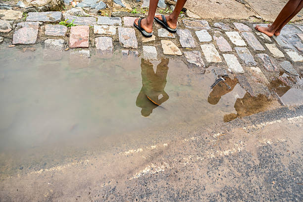 Reflection of unidentified people in a puddle. Rainwater, rainy day. Brazil