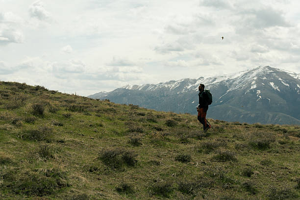 Male hiker with backpack and trekking poles enjoying a scenic hike on a grassy mountain ridge