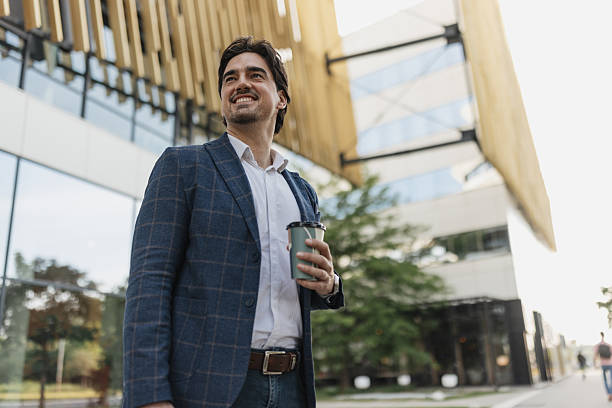 istock Man in blazer with coffee near modern architecture 2217021637