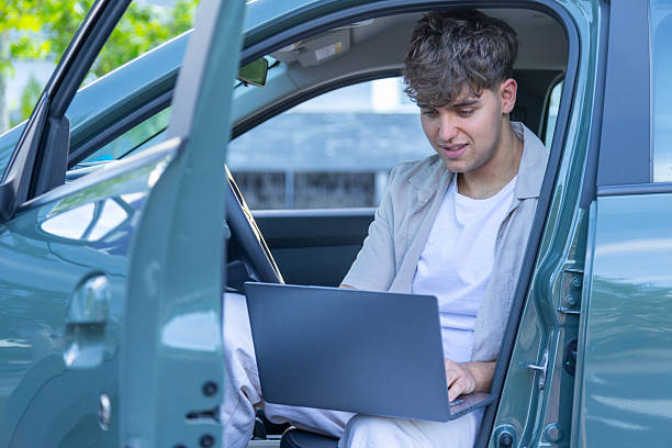 istock Young businessman working on his laptop while sitting in his car 2217030386