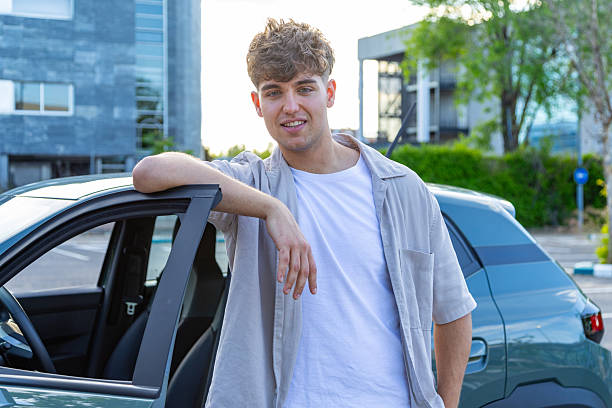 istock Young man leaning on car door smiling at camera 2217030394