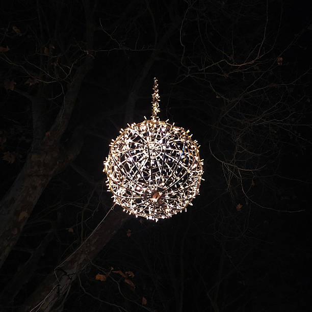 istock Atmospheric nighttime image of a glowing spherical light decoration, hanging from a tree. Celebratory mood. Great for holiday, winter, or event concepts. 2217040164