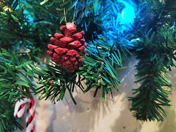 Festive pinecone ornament, handmade, hangs on a holiday tree. Captures warmth, nostalgia, and DIY spirit. Suitable for seasonal projects, greetings, backgrounds.