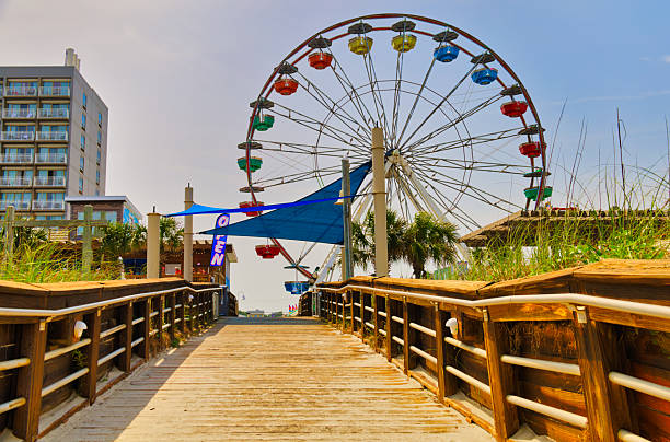 A nice summer view up a wooden ramp to the romantic boardwalk by the Ferris wheel at the Carolina Beach Amusement Park in Wilmington, North Carolina USA.