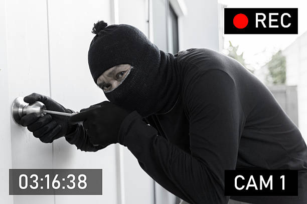 istock Masked burglar caught on surveillance camera while breaking into house with screwdriver at night crime 2217050220