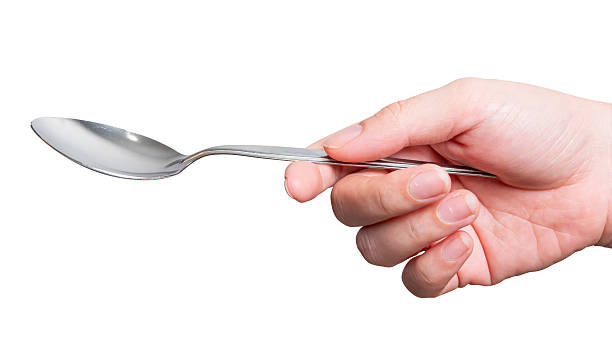 istock Female hand holding a silver steel spoon isolated on white background. 2217051365