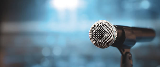 istock Microphone Public speaking background, Close up microphone on stand for speaker speech presentation stage performance with blur and bokeh light background. 2217051725