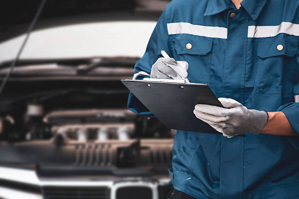 istock Car care maintenance and servicing, Close-up hand technician auto mechanic checking inspection list after repairing change spare part car engine problem and car insurance service. 2217051874