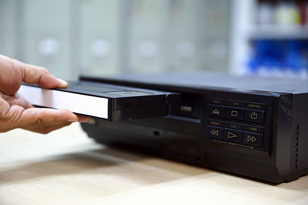 istock Close-up hand put or insert video cassette tape VHS old retro style on video record playback concept of vintage electric and electronic appliances multimedia player device old fashioned. 2217052926