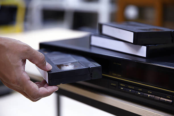 istock Close-up hand put or insert video cassette tape VHS old retro style on video record playback concept of vintage electric and electronic appliances multimedia player device old fashioned. 2217052966