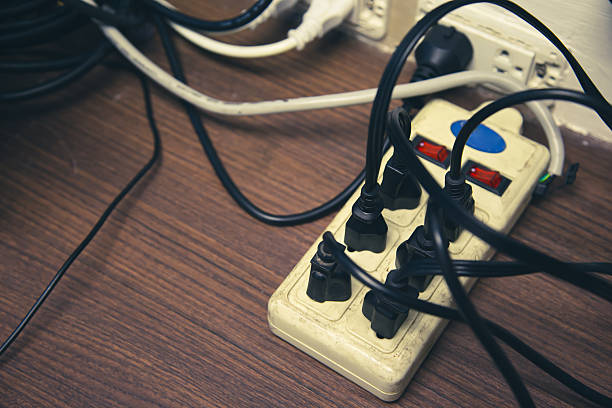 istock Old and damaged electric adapter power plug has many appliances are plugged outlet socket concept of risk danger overloaded current electrical. 2217053104