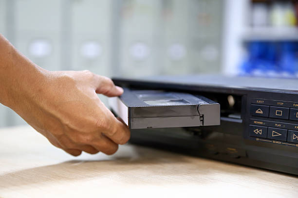 istock Close-up hand put or insert video cassette tape VHS old retro style on video record playback concept of vintage electric and electronic appliances multimedia player device old fashioned. 2217054020