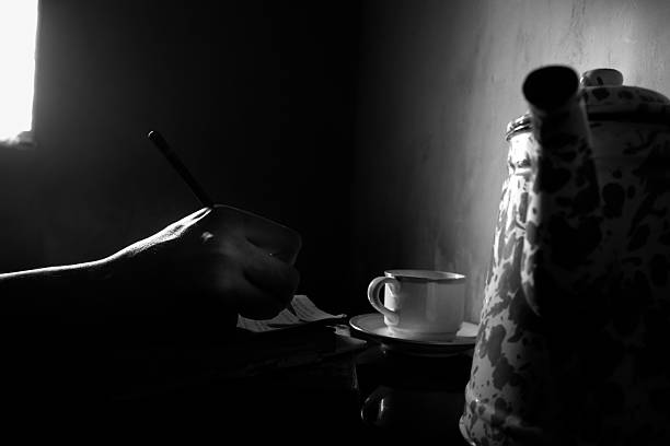 a person's hand writing in a book and accompanied by a cup of coffee