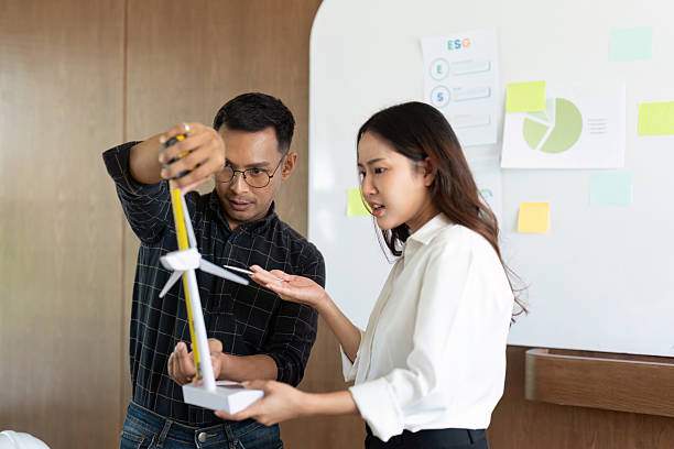 istock Sustainability in Engineering. Engineers discussing wind turbine model for eco-friendly project. 2217063532