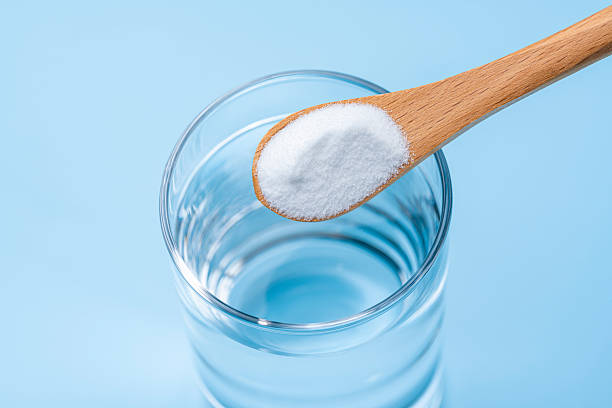 istock Adding Baking Soda to Water in Glass Cup with Wooden Spoon 2217064944