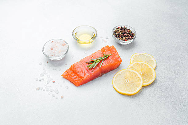 istock Fresh salmon fillet prepared with lemon, salt, and herbs on gray surface 2217067930