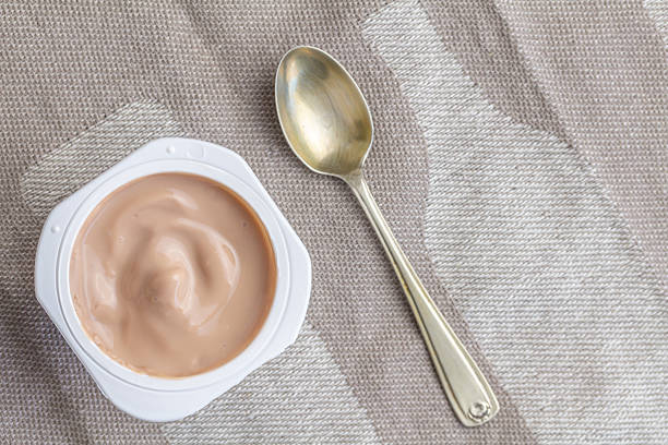 istock Yogurt in plastic pot with small spoon - overhead photo 2217068334