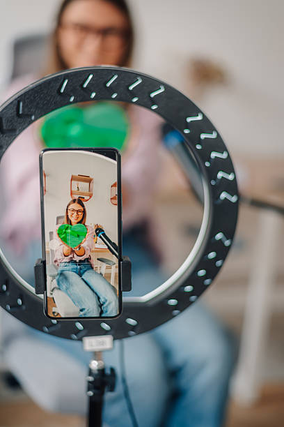 istock Influencer making a video with a ring light and showing a green heart 2217069788