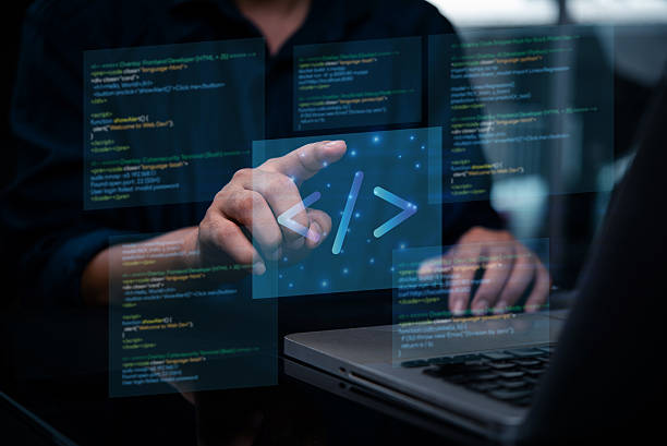 Programmer or developer working on laptop, with virtual screens displaying programming code and a coding icon. software engineering development web and intricate process of creating digital solutions. stock photo