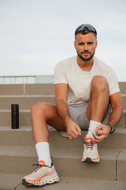 istock Sportsman tying shoelaces while sitting on stairs 2217071795