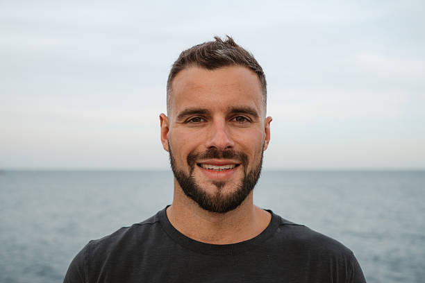 istock Handsome smiling man with beard posing in front of the sea 2217072146