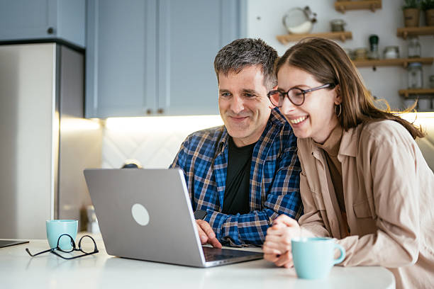 istock Two entrepreneurs sitting at a kitchen table looking at a laptop screen while enjoying a casual and comfortable moment together 2217080145