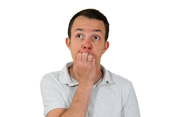 Image of concerned man with fingers near mouth and anxious expression, gazing upwards, symbolizing stress or fear. Isolated portrait