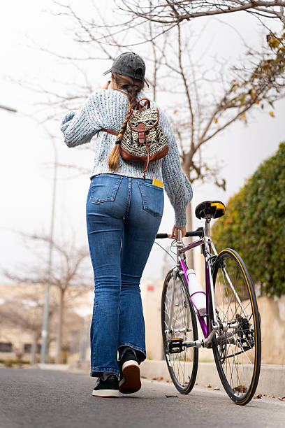 istock University student walking and holding her bicycle in urban setting 2217087821