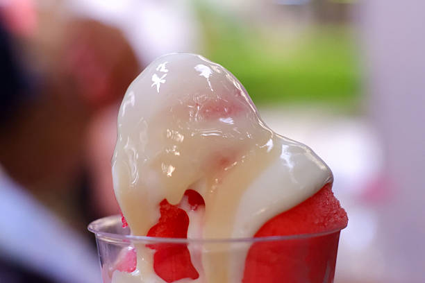 Creamy white condensed milk poured over ice cream, dessert topping, circle scoop ice cream in a cup, shop, department store, close-up of stretchy condensed milk, very sweet, colorful background image