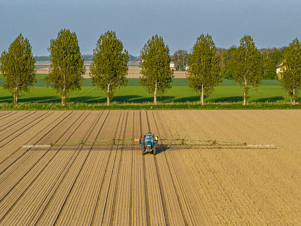 Agricultural crops sprayer spraying herbicides, pesticides or fertilizers on an agricultural field during springtime in Flevoland, Netherlands.