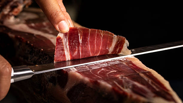 istock Knife sliced Iberian acorn-fed ham on a black background with copy text and focus selection 2217089670