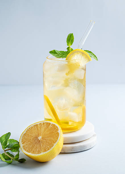 istock Iced drink with lemon and mint in a glass on a marble stand on light background 2217091375