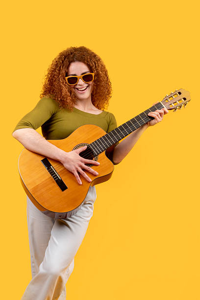 istock Redhead woman joyfully playing guitar in studio 2217091975