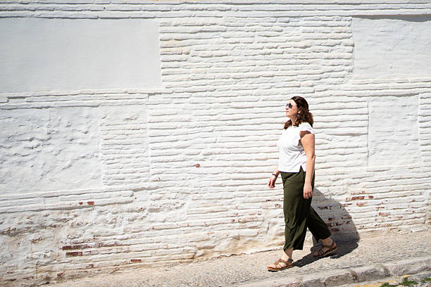 istock Tourist walking along white brick wall in sunny day with copy space 2217092403