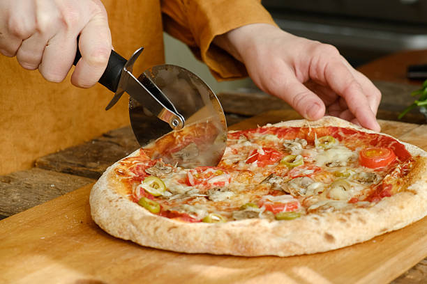 istock Pizza cutter cuts baked pizza with mushrooms and olives 2217093392