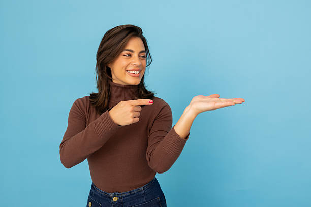 istock Cheerful female gesturing, displaying empty palm with excitement, standing against bright blue studio backdrop 2217095497