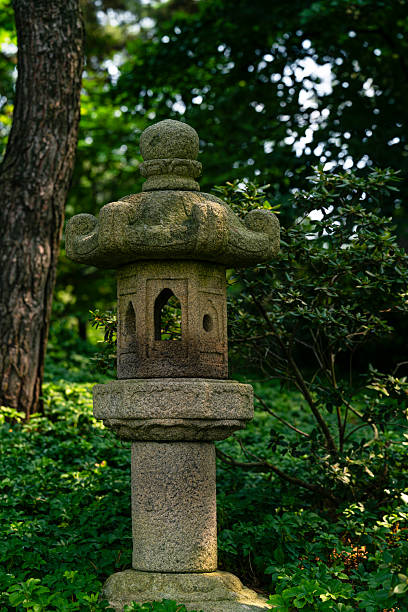 istock Traditional stone lantern standing in a lush green garden 2217096253