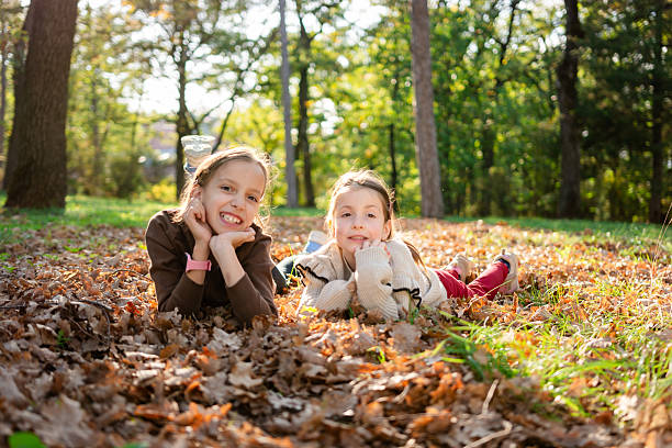 Happy two girls lying in autumn leaves in park