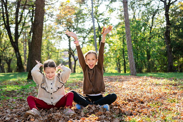 Carefree children playing whit autumn leaves in park