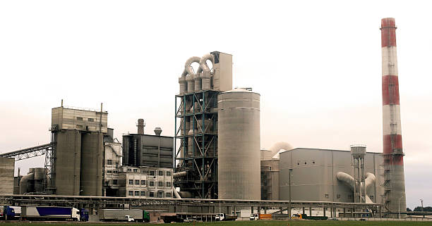 istock Factory complex with large smokestack and industrial structures near a shipping area during overcast weather 2217098446